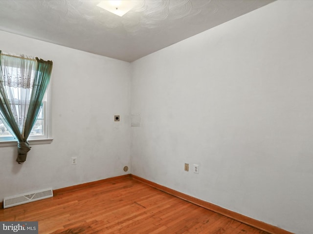 empty room featuring visible vents, baseboards, and wood finished floors