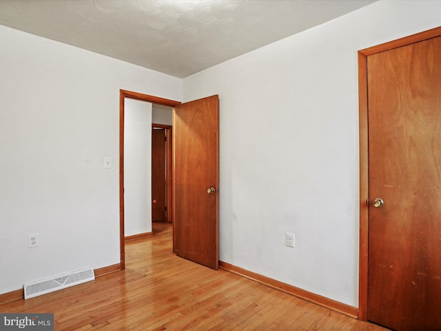 spare room with light wood finished floors, baseboards, and visible vents