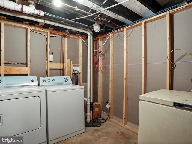 unfinished basement featuring fridge and separate washer and dryer