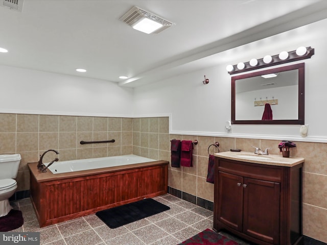 full bath with toilet, a wainscoted wall, visible vents, tile walls, and a bath