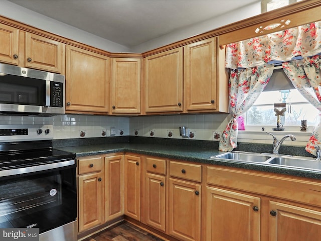 kitchen featuring dark countertops, tasteful backsplash, stainless steel appliances, and a sink