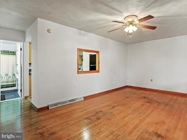 unfurnished room featuring baseboards, hardwood / wood-style floors, visible vents, and a ceiling fan