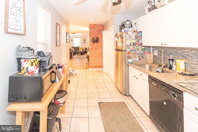 kitchen featuring white cabinets, sink, light stone countertops, black dishwasher, and light tile patterned floors