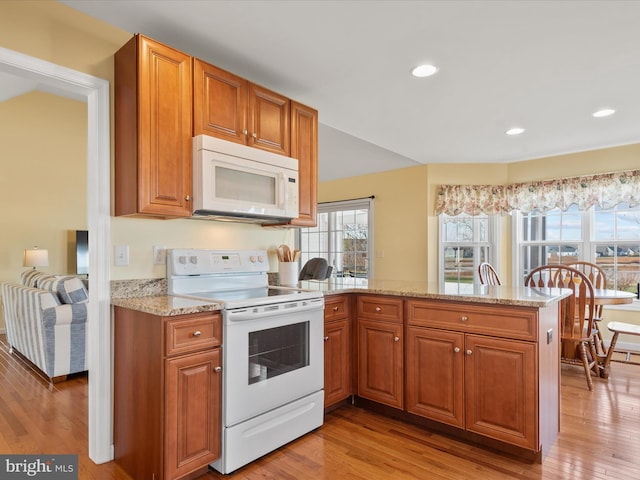 kitchen featuring white appliances, kitchen peninsula, and light wood-type flooring