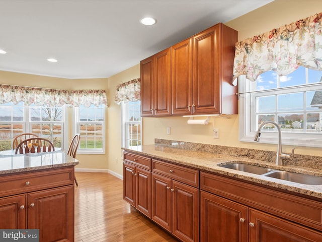 kitchen with sink, light stone counters, and light hardwood / wood-style floors