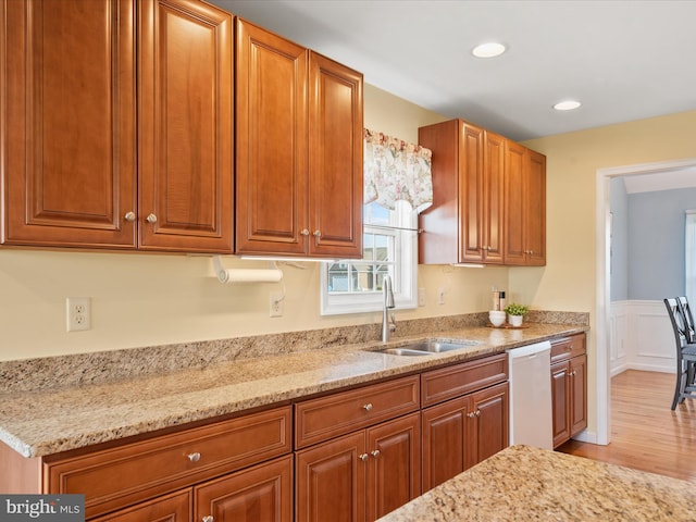 kitchen with dishwasher, light stone countertops, and sink