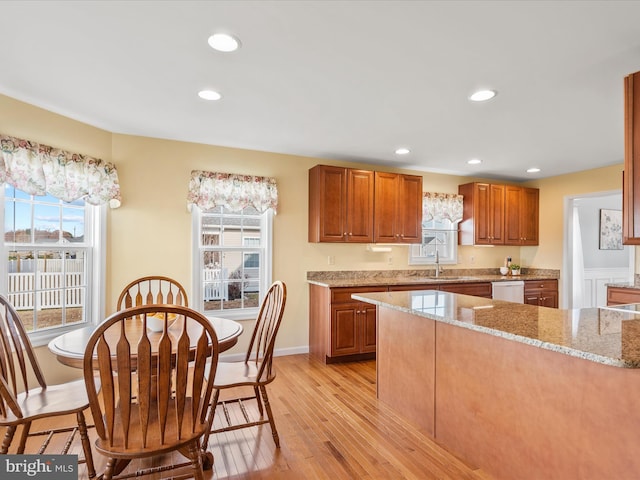 kitchen with dishwasher, light stone countertops, sink, and light hardwood / wood-style flooring