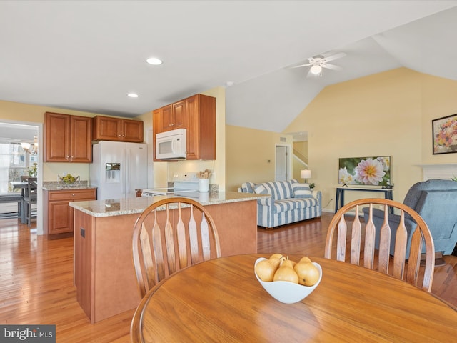 dining area featuring vaulted ceiling, ceiling fan, and light hardwood / wood-style flooring