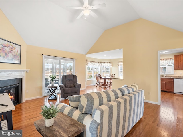 living room featuring vaulted ceiling, ceiling fan, sink, and light hardwood / wood-style flooring