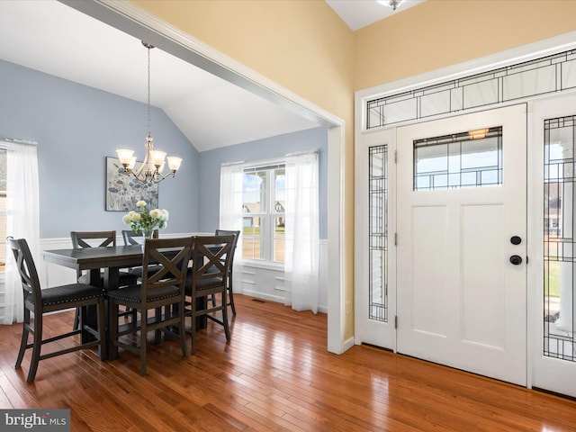 entryway featuring lofted ceiling, hardwood / wood-style flooring, and an inviting chandelier