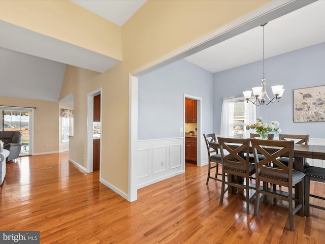 dining room with vaulted ceiling, light hardwood / wood-style floors, and a notable chandelier