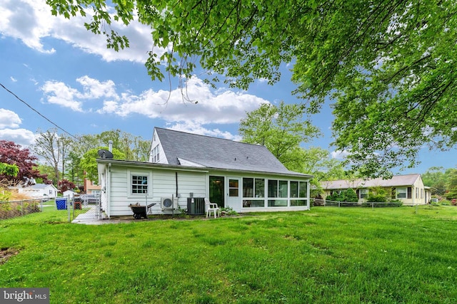 rear view of house featuring a lawn, central AC, and a sunroom