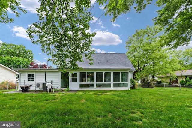 back of property with a sunroom and a lawn