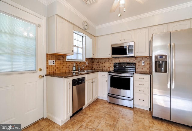 kitchen featuring white cabinetry, sink, dark stone countertops, crown molding, and appliances with stainless steel finishes