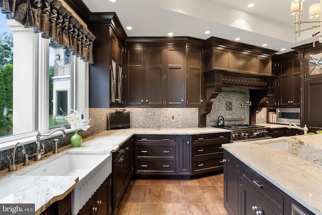 kitchen featuring decorative backsplash, pendant lighting, high end stainless steel range, and a healthy amount of sunlight