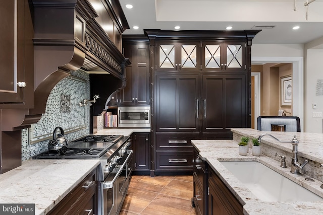 kitchen with sink, light stone countertops, stainless steel appliances, and tasteful backsplash