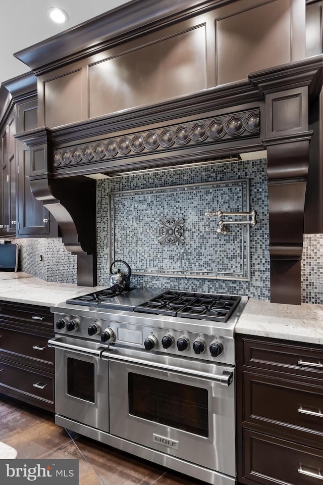 kitchen with dark brown cabinets, tasteful backsplash, double oven range, and light stone counters