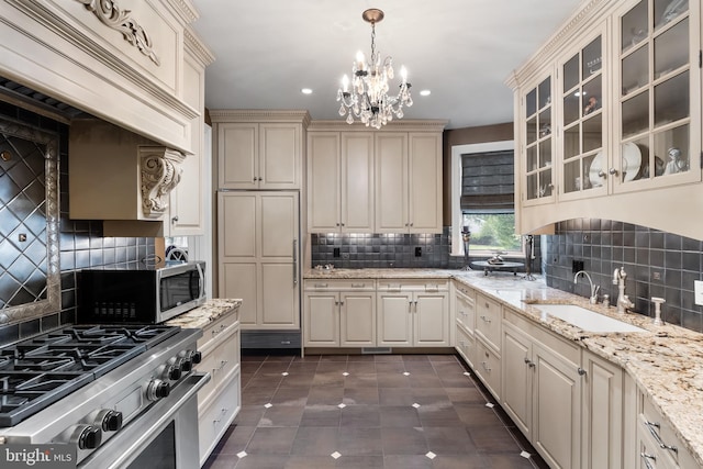 kitchen with sink, stainless steel appliances, tasteful backsplash, cream cabinets, and decorative light fixtures