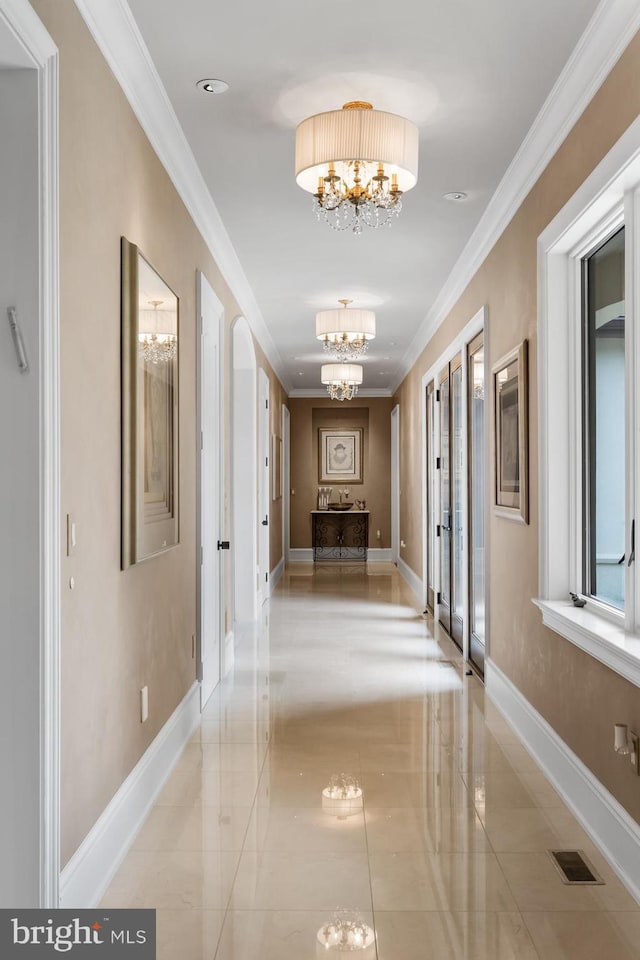 hall with ornamental molding and a chandelier