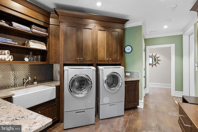 clothes washing area with cabinets, ornamental molding, sink, light tile patterned floors, and separate washer and dryer