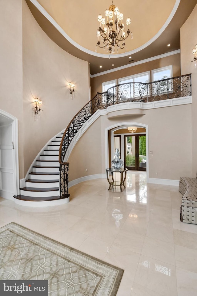 foyer entrance featuring french doors, an inviting chandelier, crown molding, and a high ceiling