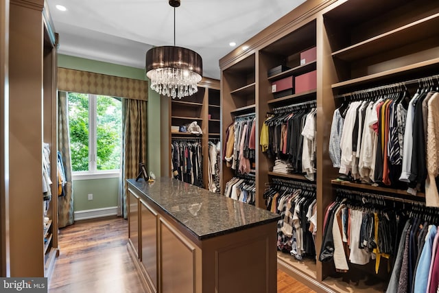 spacious closet with wood-type flooring and a chandelier