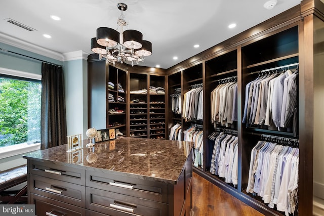 walk in closet with dark hardwood / wood-style flooring and a notable chandelier