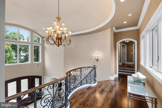 interior space with ornamental molding, hardwood / wood-style flooring, a raised ceiling, and a notable chandelier