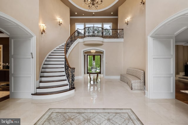 foyer with a high ceiling, a notable chandelier, and ornamental molding