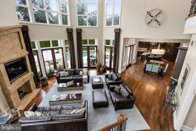 living room featuring a fireplace, plenty of natural light, a towering ceiling, and dark hardwood / wood-style floors