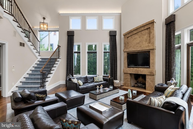 living room with hardwood / wood-style flooring, a towering ceiling, and a fireplace