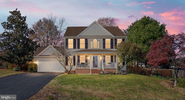 colonial inspired home with a lawn, a porch, and a garage