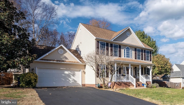 colonial house featuring a porch, a garage, and a front yard