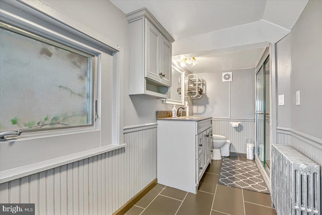 bathroom with walk in shower, vanity, tile patterned flooring, radiator heating unit, and toilet