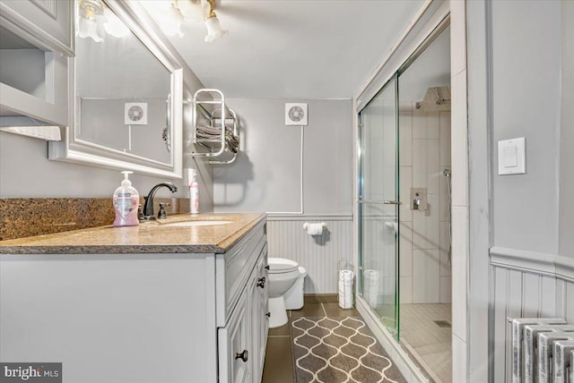 bathroom with radiator, vanity, an enclosed shower, and toilet