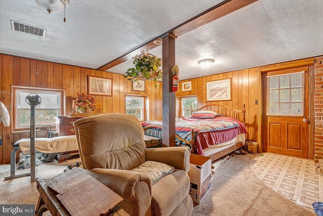 bedroom featuring multiple windows, wooden walls, and a textured ceiling