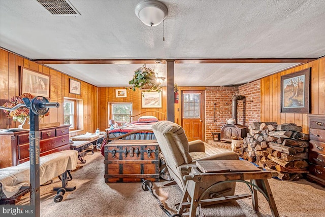 bedroom with carpet flooring, a wood stove, wood walls, and a textured ceiling