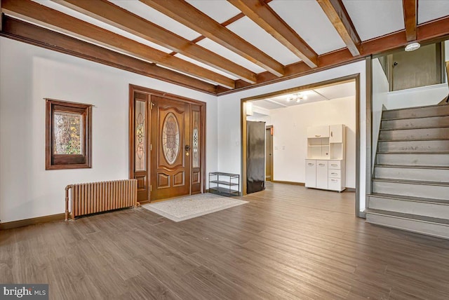 foyer entrance with hardwood / wood-style floors, beam ceiling, and radiator heating unit