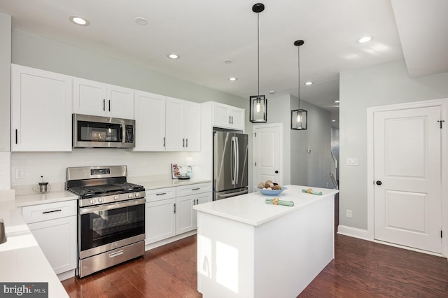 kitchen with white cabinets, a center island, dark wood-type flooring, stainless steel appliances, and hanging light fixtures