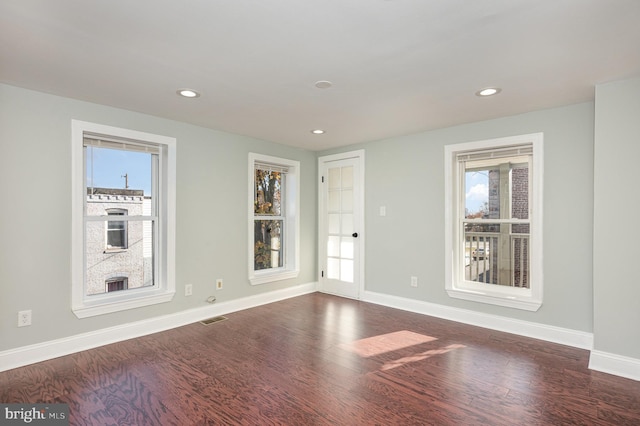 spare room featuring dark wood-type flooring and plenty of natural light