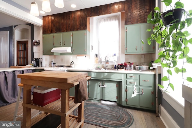 kitchen featuring backsplash, light hardwood / wood-style flooring, green cabinetry, and sink