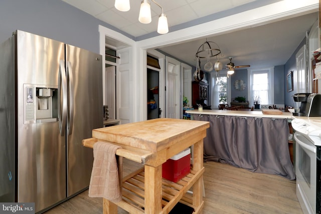 kitchen with pendant lighting, white range, stainless steel refrigerator with ice dispenser, ceiling fan, and kitchen peninsula