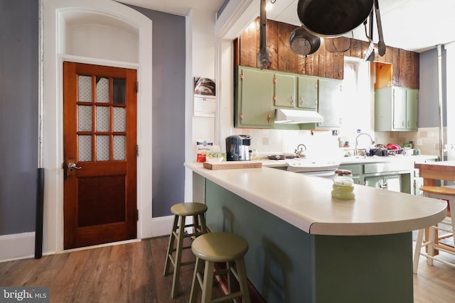 kitchen featuring backsplash, kitchen peninsula, dark hardwood / wood-style flooring, and a breakfast bar area