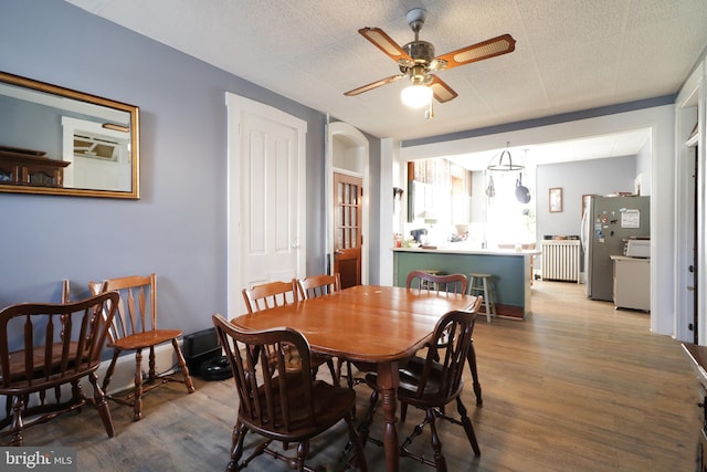 dining space featuring ceiling fan, wood-type flooring, and a textured ceiling