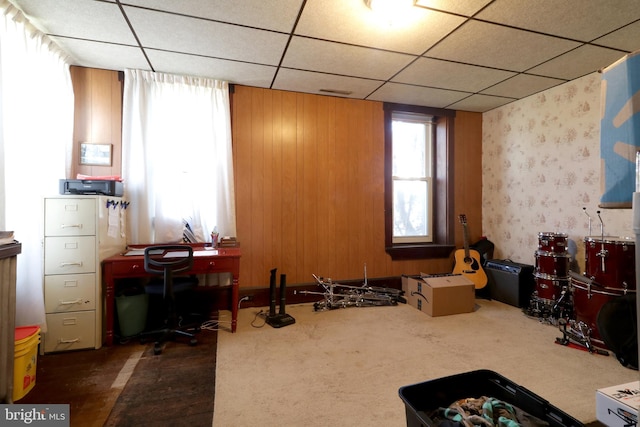 misc room featuring a paneled ceiling, wood walls, and dark carpet