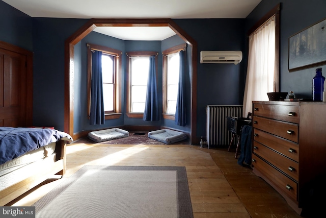 bedroom featuring radiator heating unit, a wall mounted AC, and dark wood-type flooring