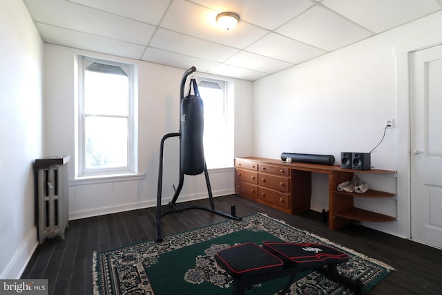 workout room with a paneled ceiling, dark hardwood / wood-style floors, and radiator