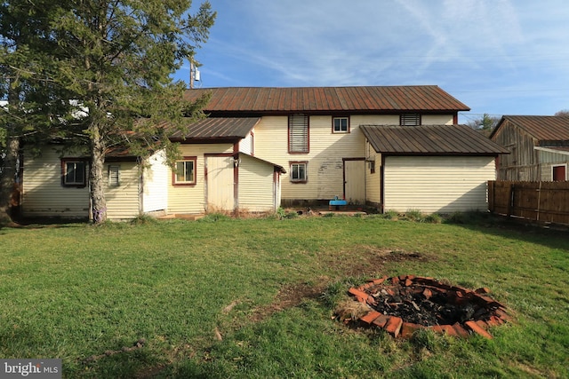 back of house with a yard and an outdoor fire pit