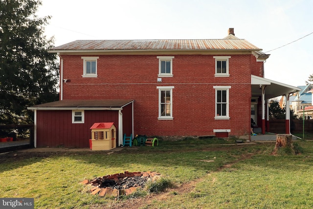 rear view of property with a yard and a fire pit