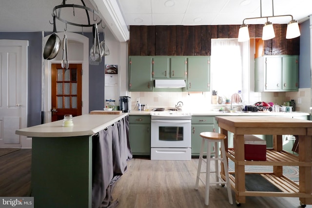 kitchen with decorative backsplash, white electric range oven, green cabinetry, and light hardwood / wood-style floors